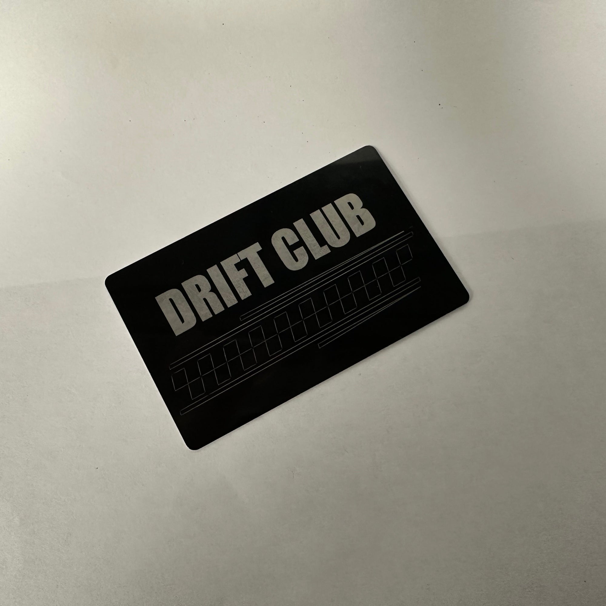 Black card with 'DRIFT CLUB' text on a metallic surface